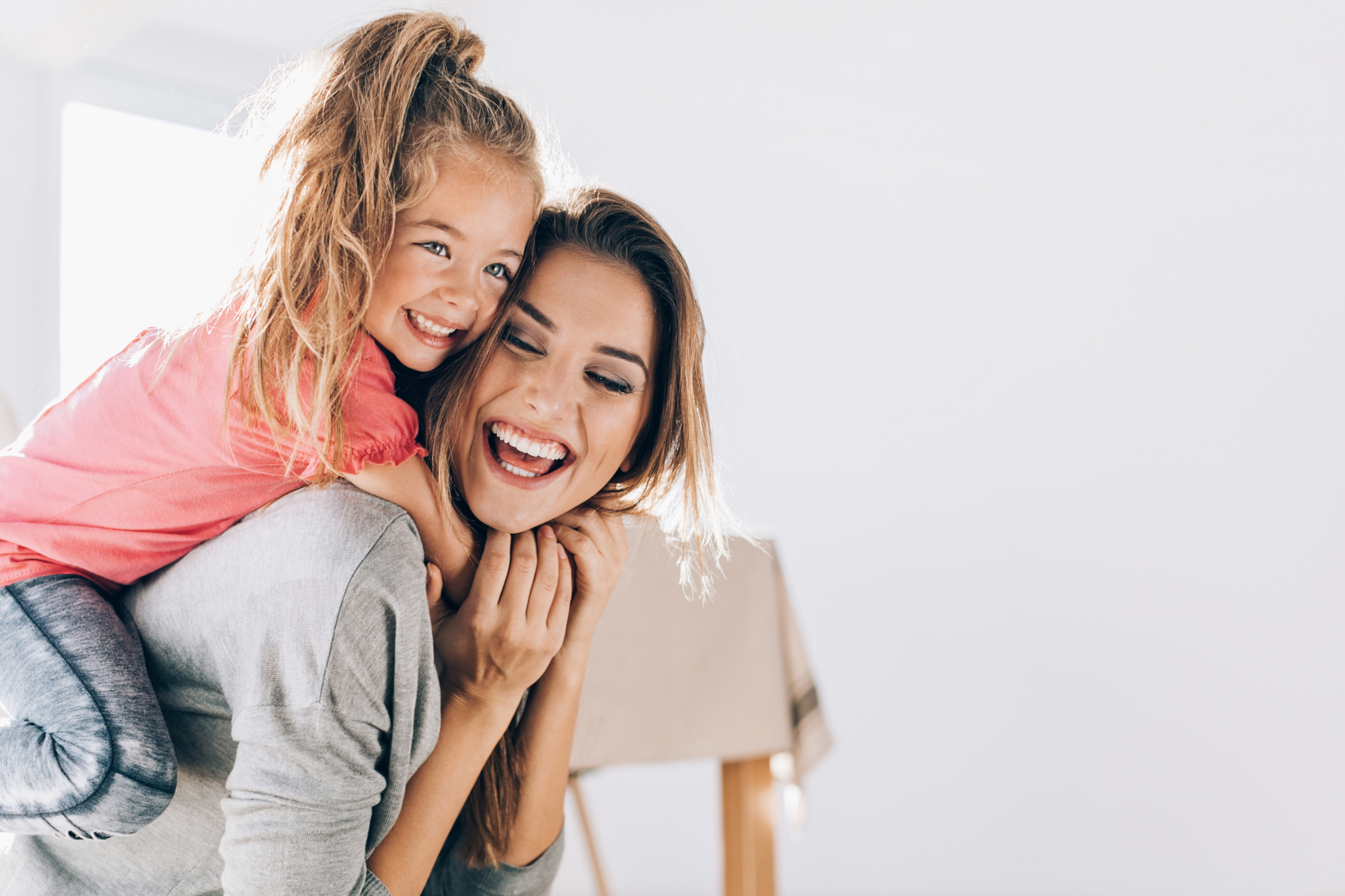Woman smiling with a child on her back.